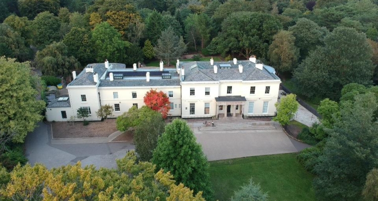 A drone shot view of the eighteenth century mansion house from above, the green trees of Calderstones Park surround the house