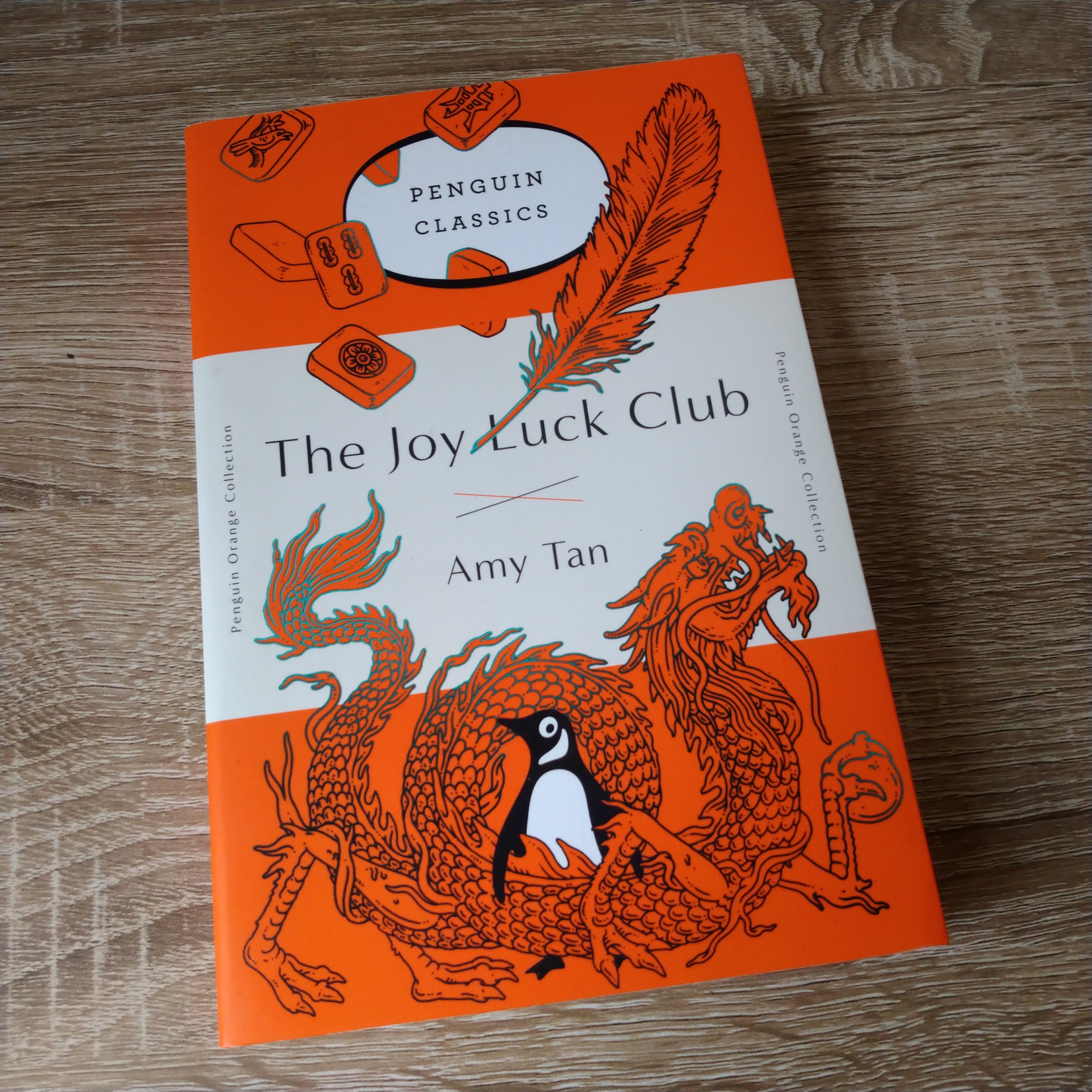 An image of a book with an orange penguin classics cover illustrated with an intricate dragon and feathers around the traditional penguin logo