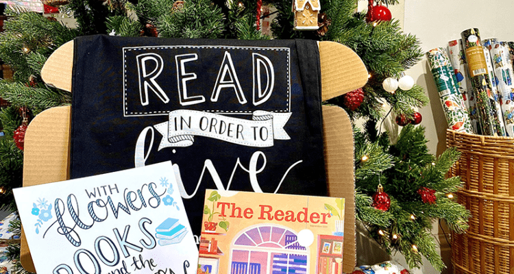 The Reader magazine placed in the centre surrounded by other literary gifts, all placed in front of a Christmas tree.