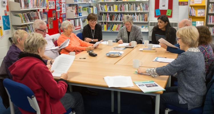 Group members and volunteers sitting around a table during a Shared Reading session.