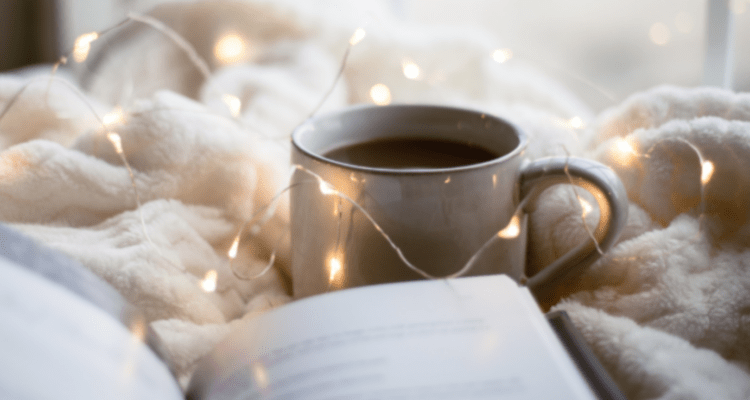 Cosy coffee cup in bed with a book and fairy lights