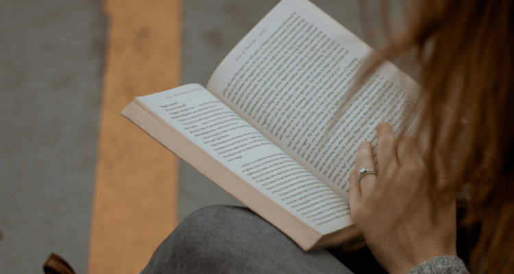 Hand resting on a book as a person reads